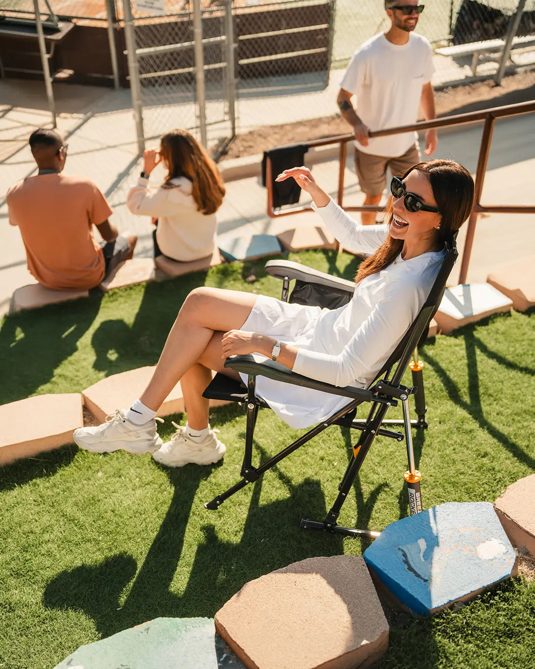 A woman sitting in a black BreezeRocker while attending a baseball game. 