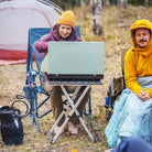 Two people at a campsite using a cooking stove beside a Teal Breeze Rocker.