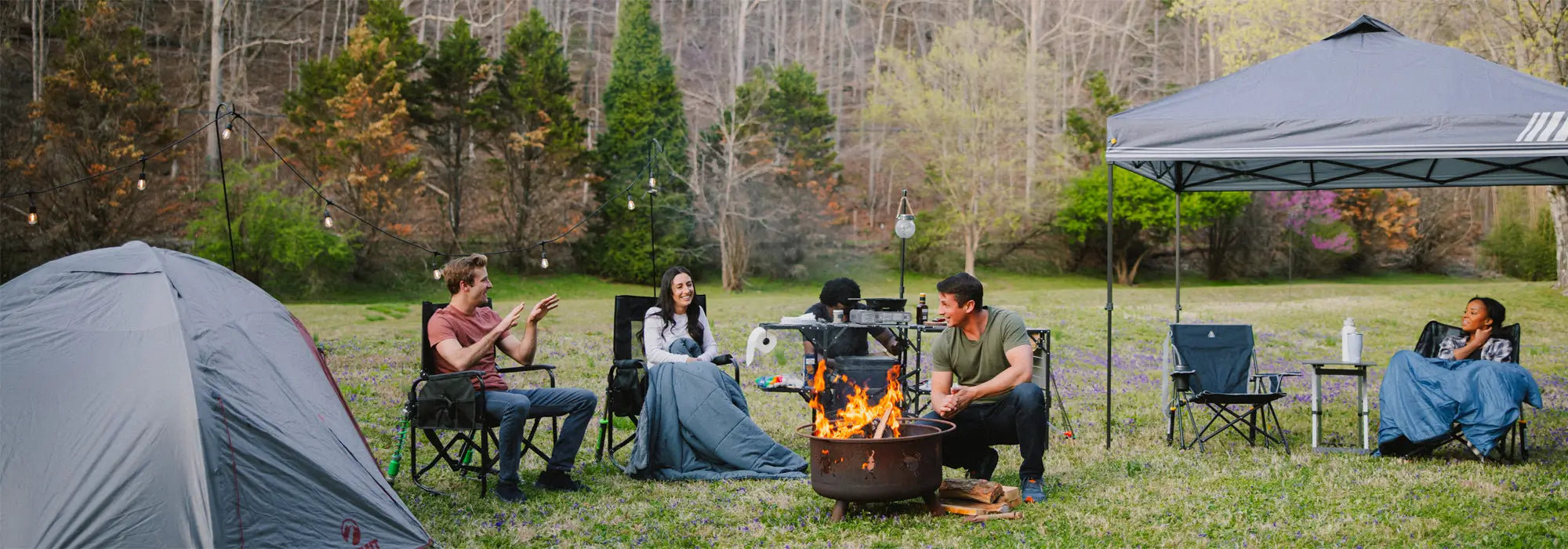 A group of people sitting around a firepit while sitting in GCI Outdoor chairs. 