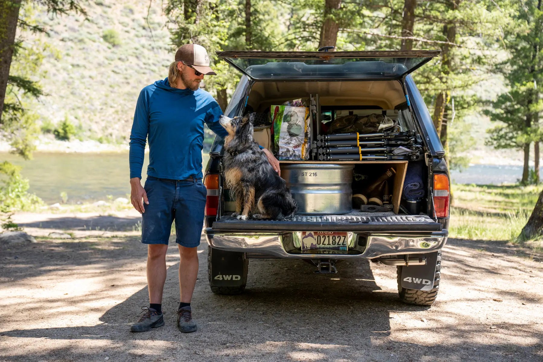 Man petting his dog sitting on a tailgate with stowaway rockers packed in his truck.