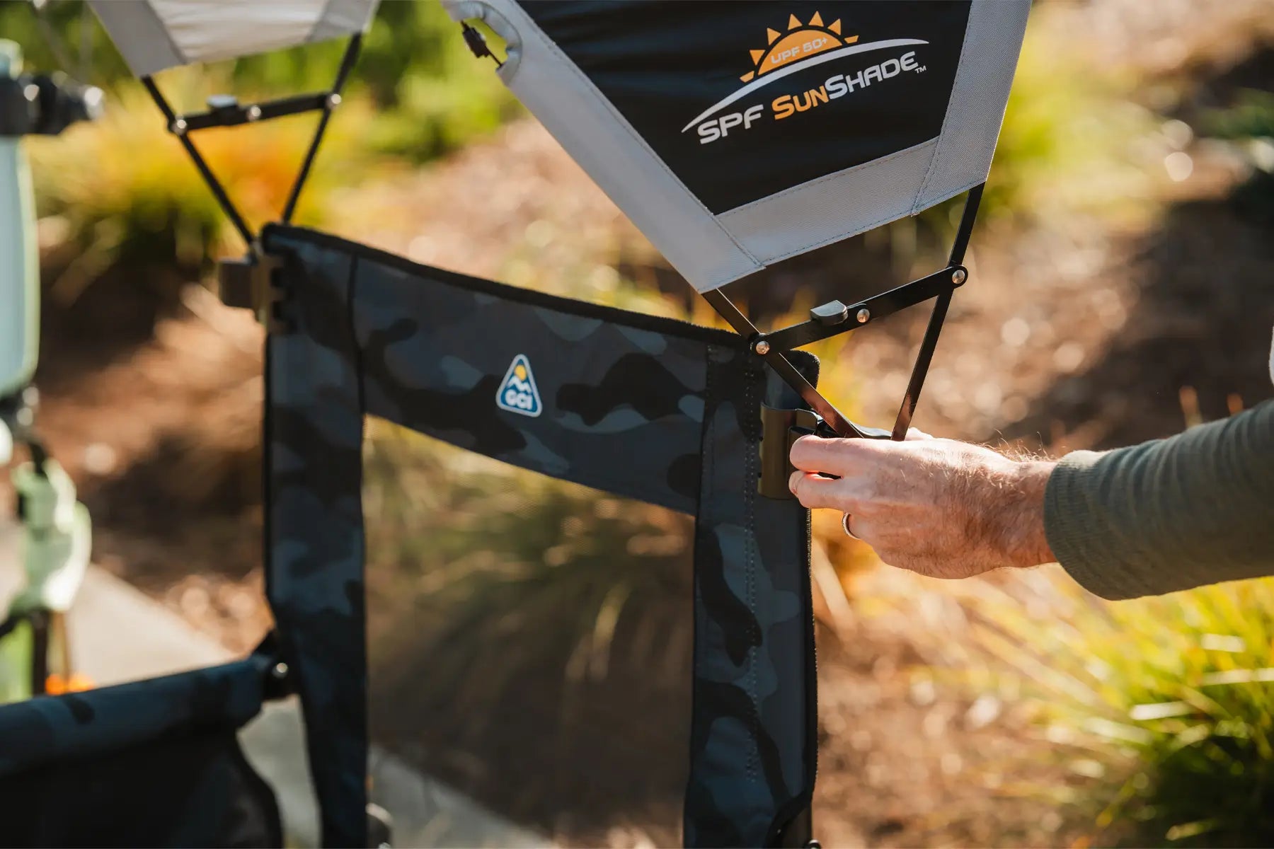 Person clipping a sunshade accessory onto their stowaway rocker chair.