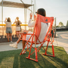 Woman cheering at a softball game from a GCI Outdoor Comfort Pro Rocker in Coral Garden, rear view.