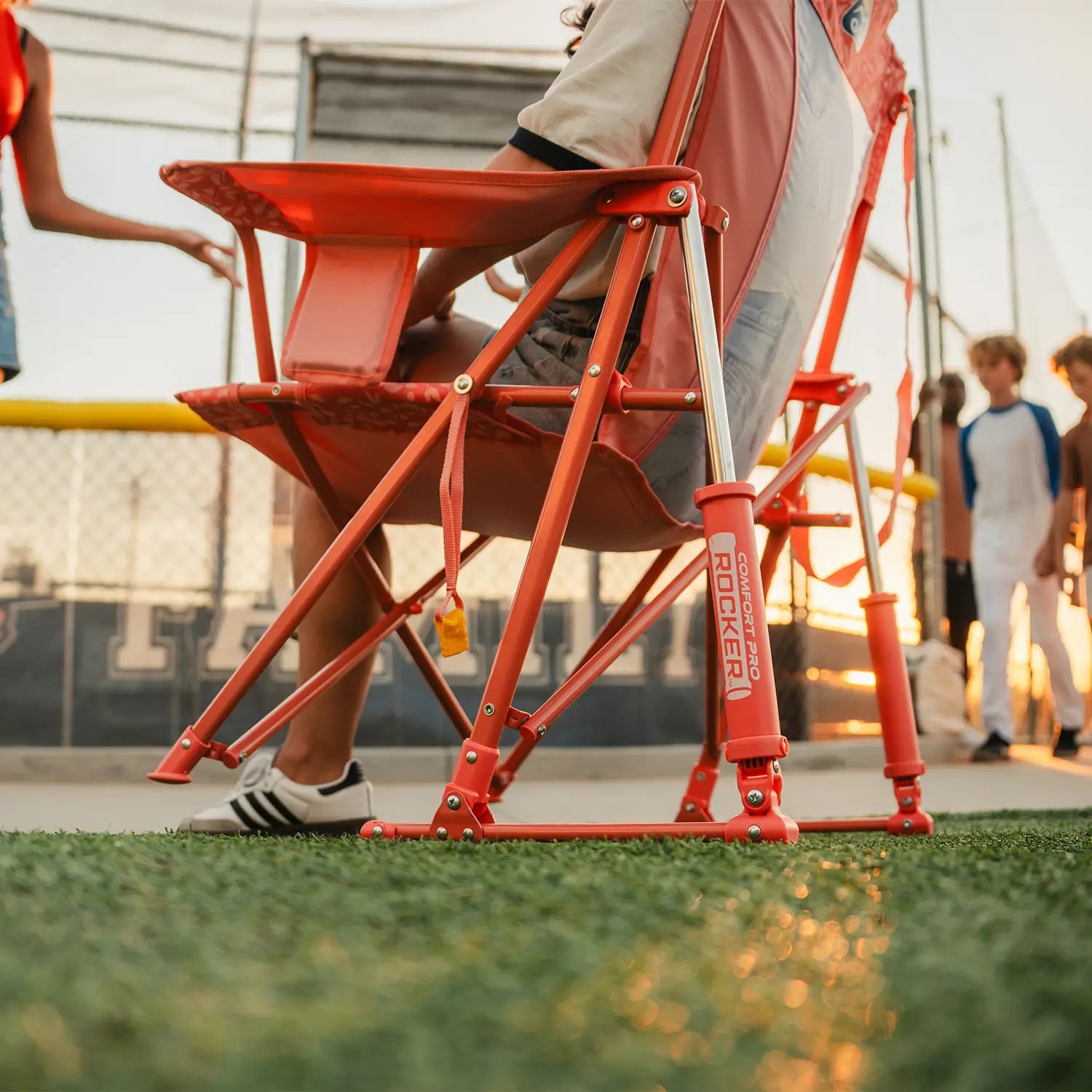 Close-up low angle view of the GCI Outdoor Comfort Pro Rocker in Coral Garden frame and Spring-Action rocking mechanism at a baseball field.