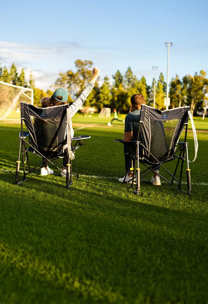 A couple cheering on soccer players while sitting in their comfort pro rocker chairs. 