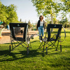 Two Comfort Pro Rockers facing a playground while a woman walks towards the chairs. 