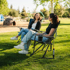 A woman sitting in a black Comfort Pro Rocker chair talking to another woman sitting in an Eazy Chair. 