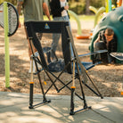 A close up of the indigo Comfort Pro Rocker next to a childrens playground. 