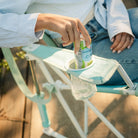 Hand placing a beverage into the built-in cup holder of the pastel green Comfort Pro Rocker.