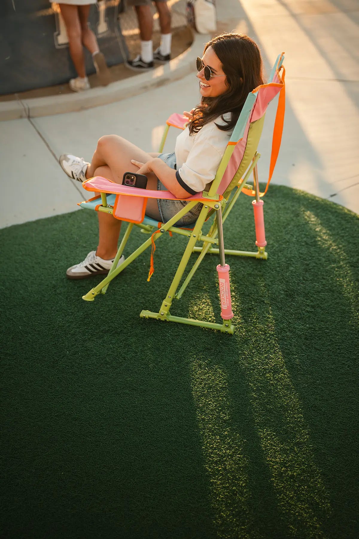 A woman sitting in a sweet tea Comfort Pro Rocker while she attends a baseball game. 