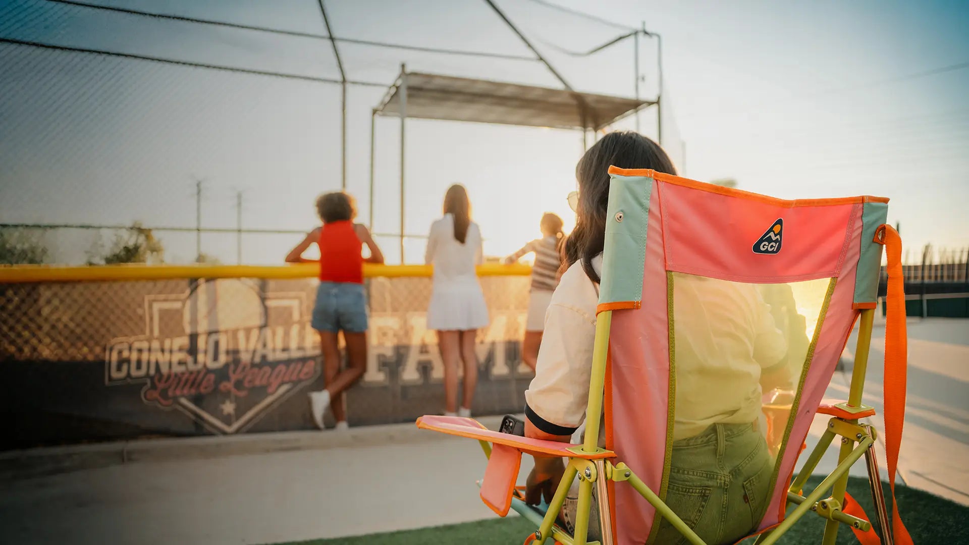 A woman sitting in a sweet tea Comfort Pro Rocker while she attends a baseball game. 