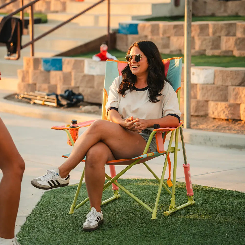 A woman sitting in a sweet tea comfort pro rocker on a patch of grass. 