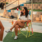 A woman sitting in a sweet tea comfort pro rocker on a patch of grass. 
