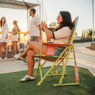 A woman sitting in a sweet tea comfort pro rocker cheering on a stadium game. 