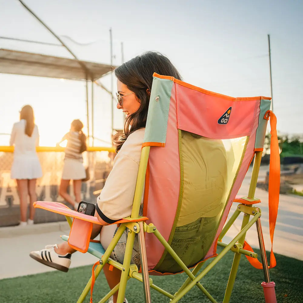 The backside of a woman sitting in a sweet tea comfort pro rocker at a baseball game. 