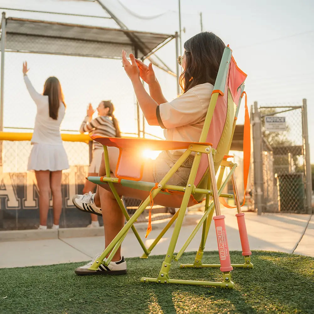 The side of a woman sitting in a sweet tea comfort pro rocker at a baseball game. 