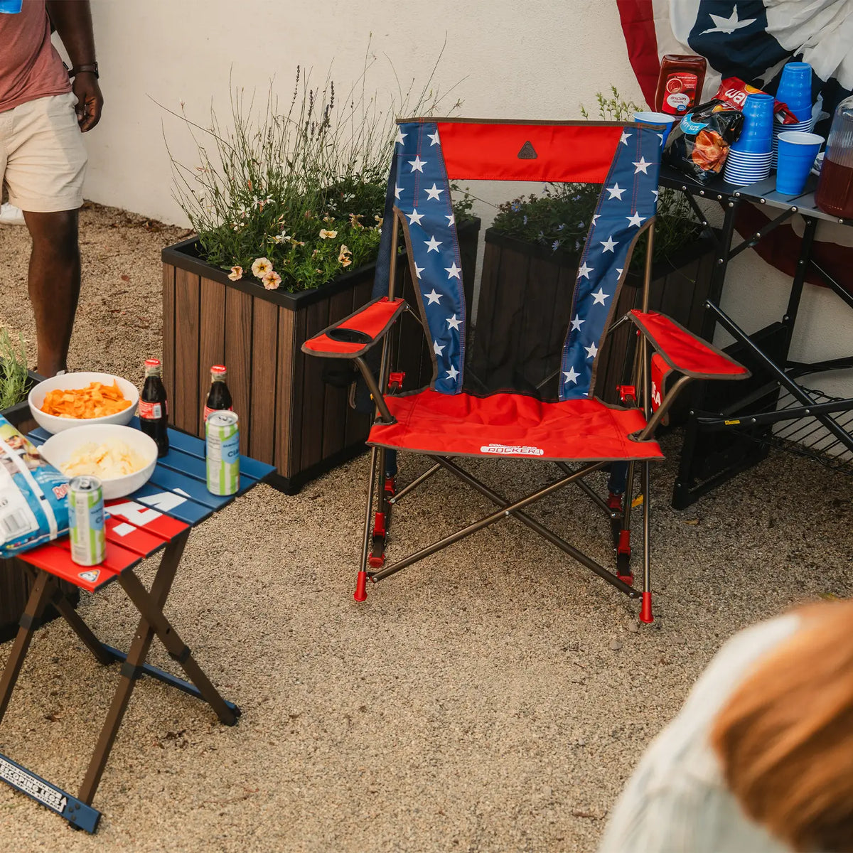 A USA Comfort Pro Rocker and table positioned next to a group of people in a backyard. 
