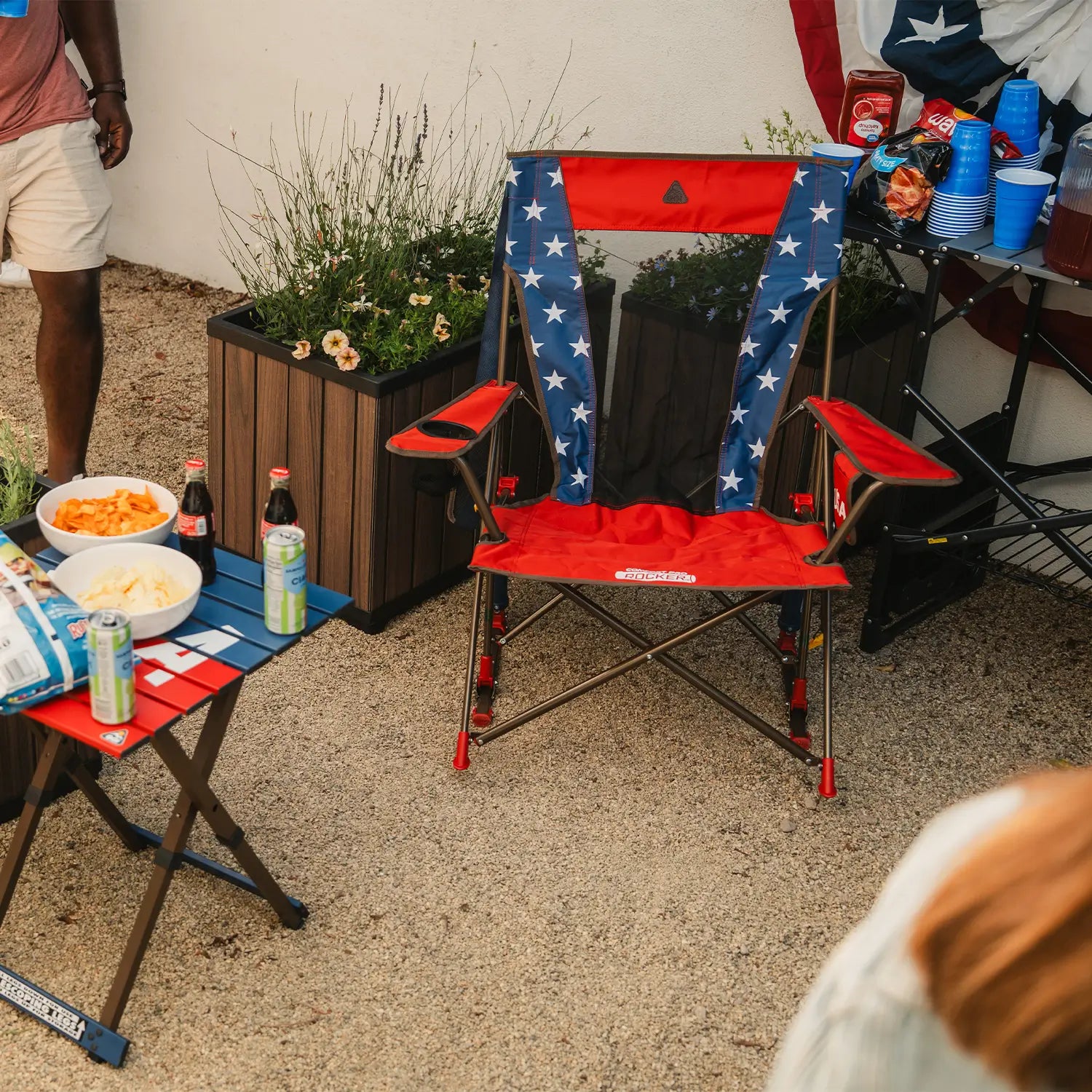 A USA Comfort Pro Rocker and table positioned next to a group of people in a backyard. 