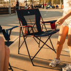 A woman preparing to sit down in the indigo/red Comfort Quad Chair. 