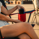 A phone being removed from the phone pocket on the indigo/red Comfort Quad Chair. 