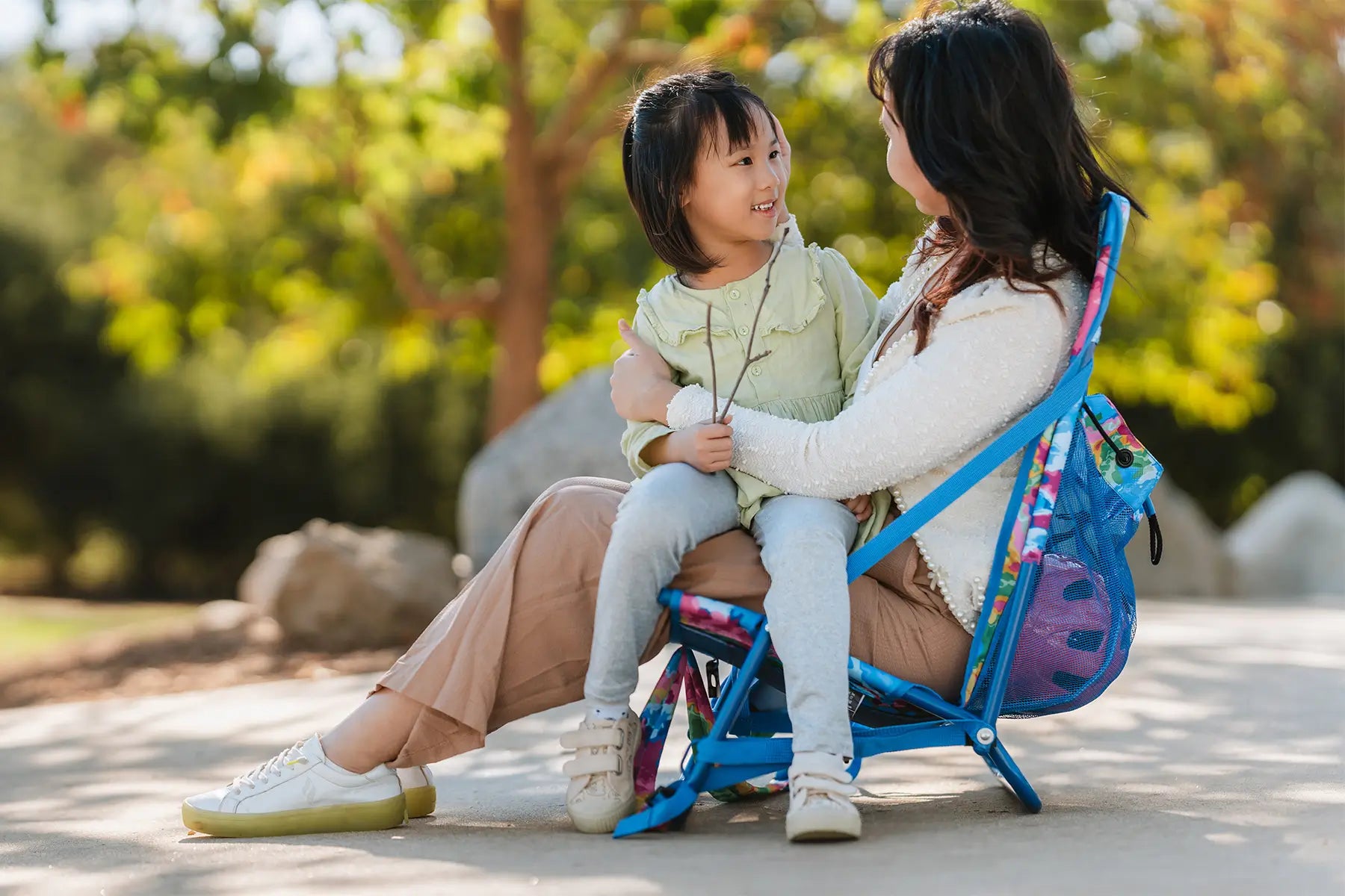 A mother and daughter sit together on a colorful Everywhere Chair 2, smiling and enjoying the outdoors.