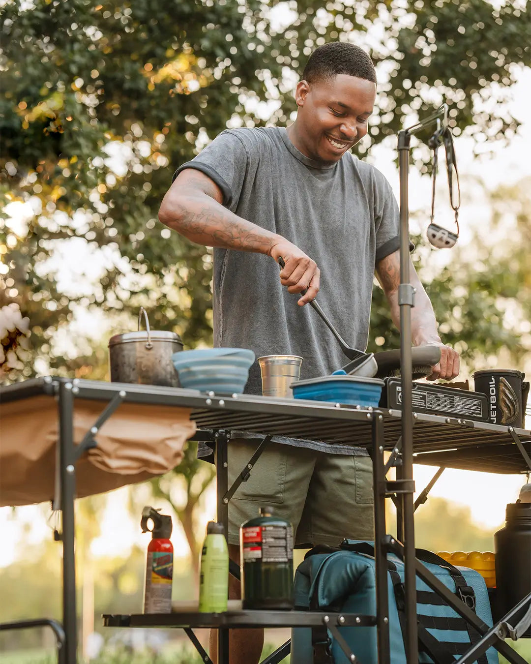 A man cooking food using a GCI Outdoor cook station. 