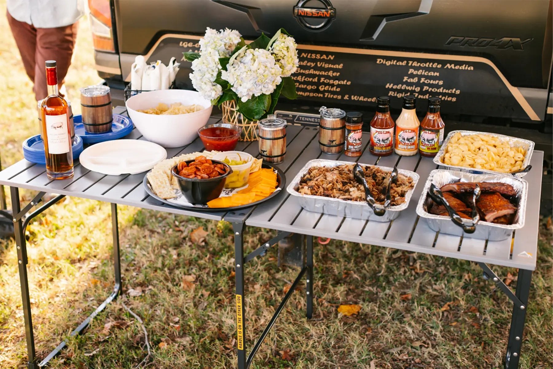 A bunch of bbq catered snacks sitting on top of the slim-fold table. 