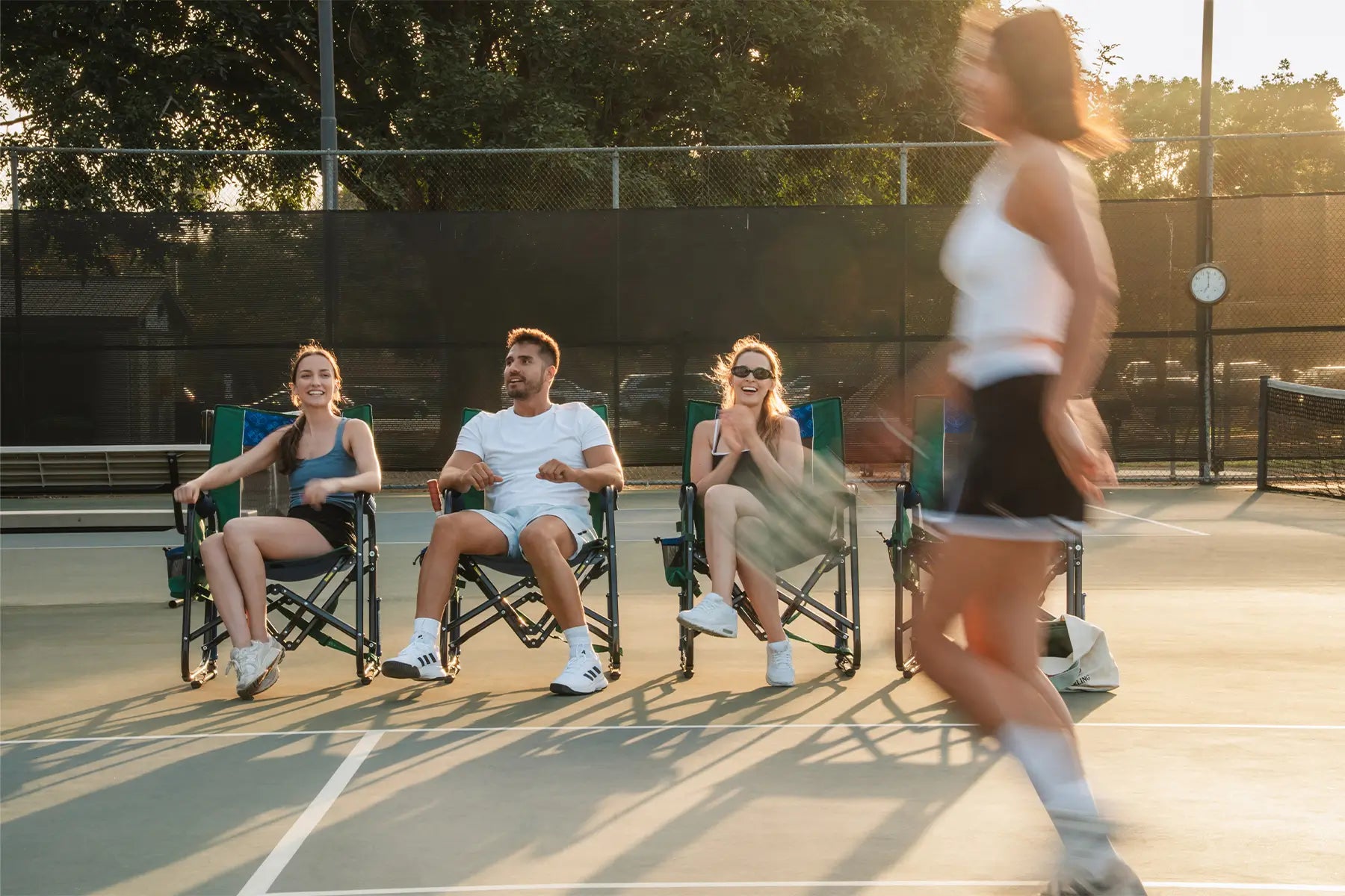 A group of people sitting in pickleball Stowaway Rockers watching players play Pickleball. 
