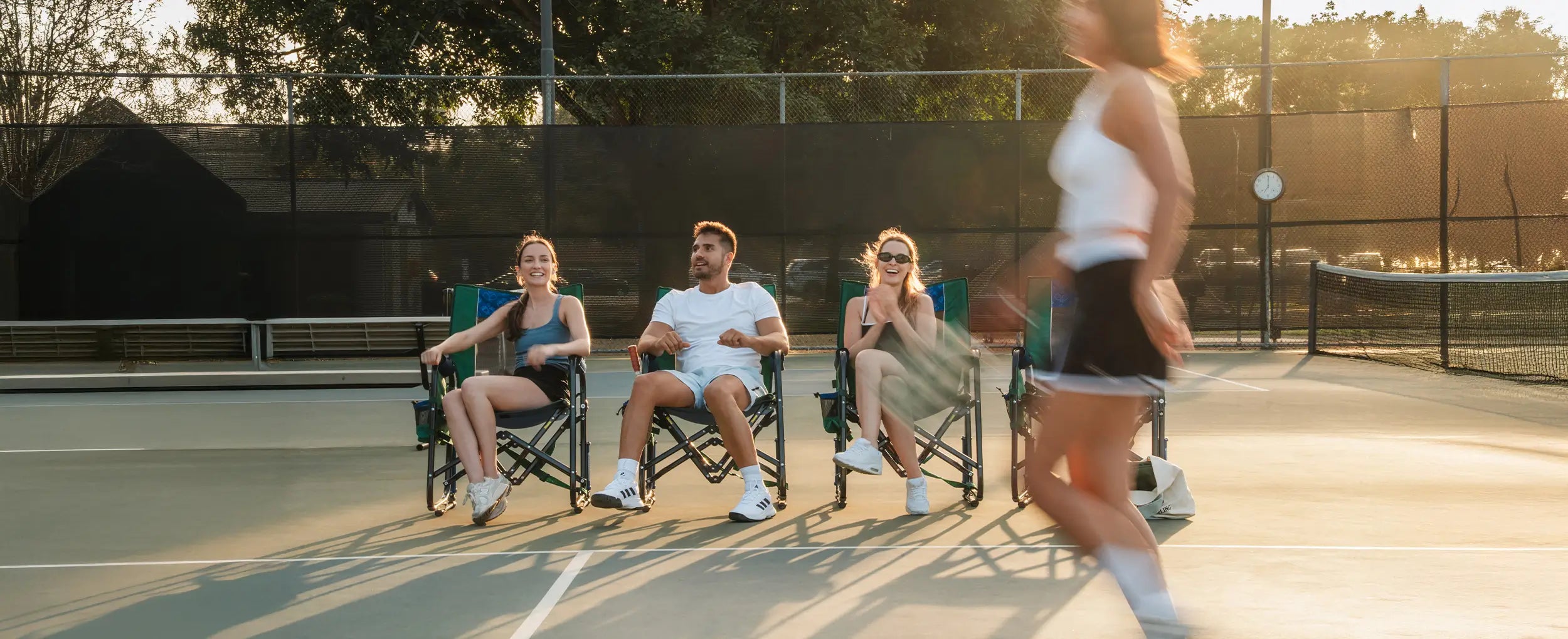 A group of people sitting in pickleball Stowaway Rockers watching players play Pickleball. 