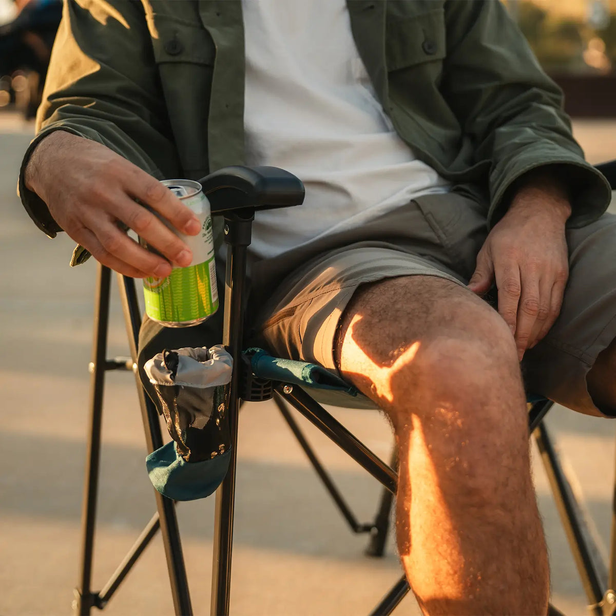 A man pulling his beverage out of the cup holder of the teal Eazy Chair. 