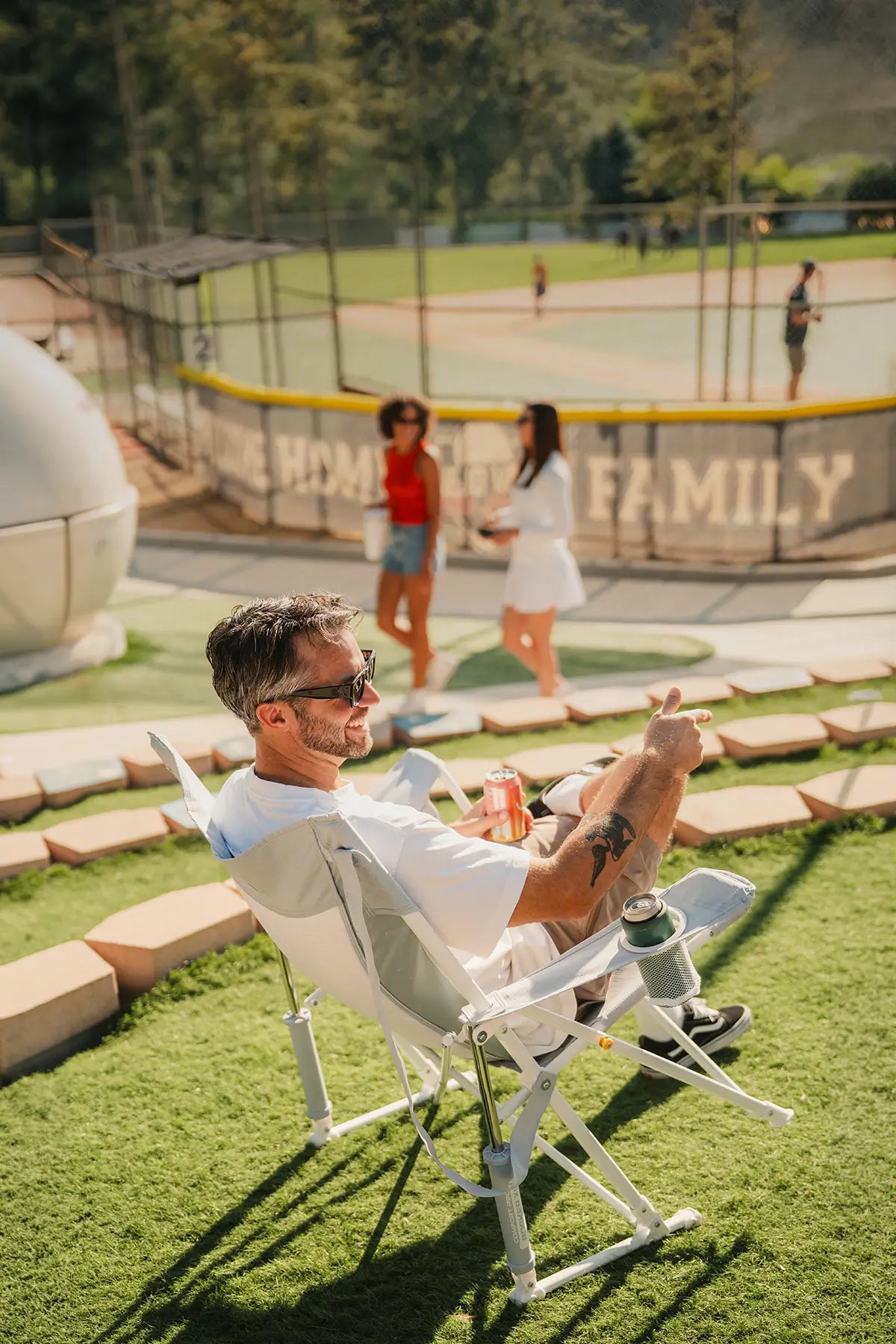 A man sitting in a pastel Comfort Pro Rocker XL attending a baseball game. 