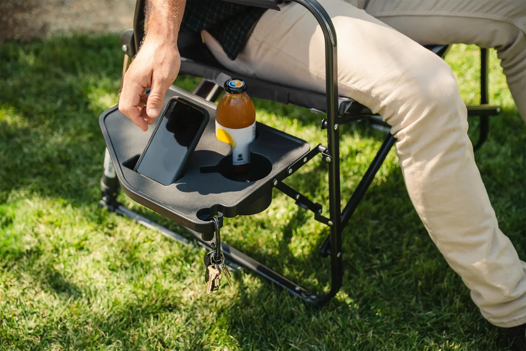 A man reaching for his phone positioned on his side table on his Stowaway Rocker with Side Table chair. 