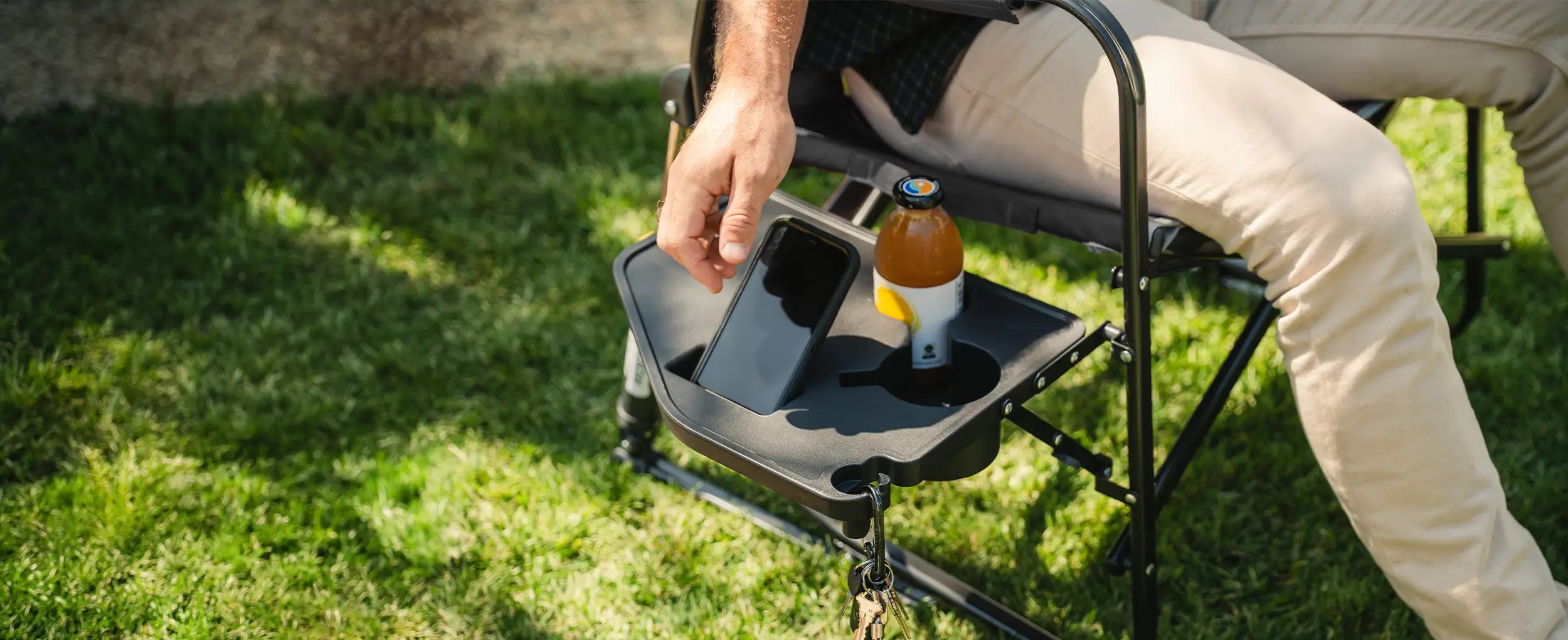 A man reaching for his phone positioned on his side table on his Stowaway Rocker with Side Table chair. 