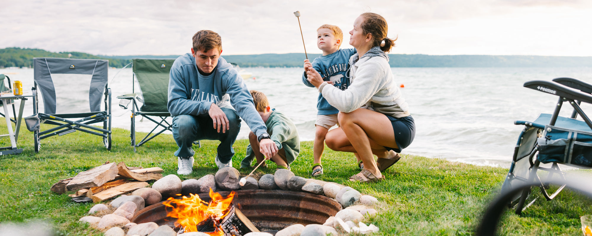 Person sitting in a GCI Firepit Rocker by a firepit at a campsite, roasting marshmallows.