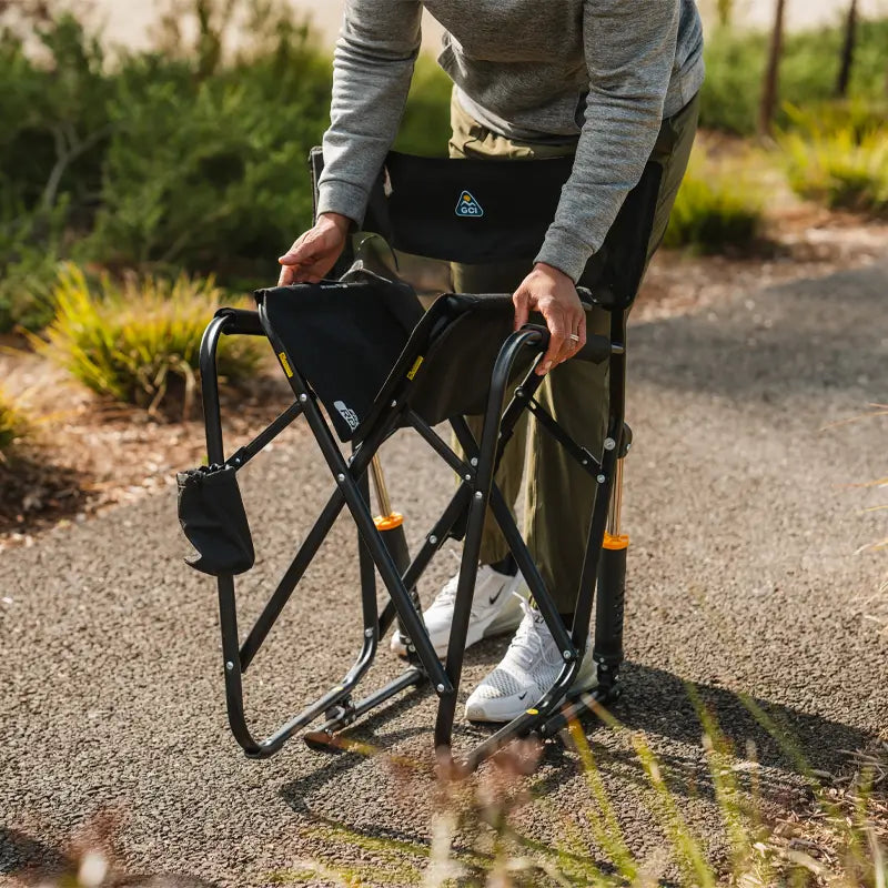 A person folding the Freestyle Rocker Elite chair, showing its compact, easy-to-carry design.