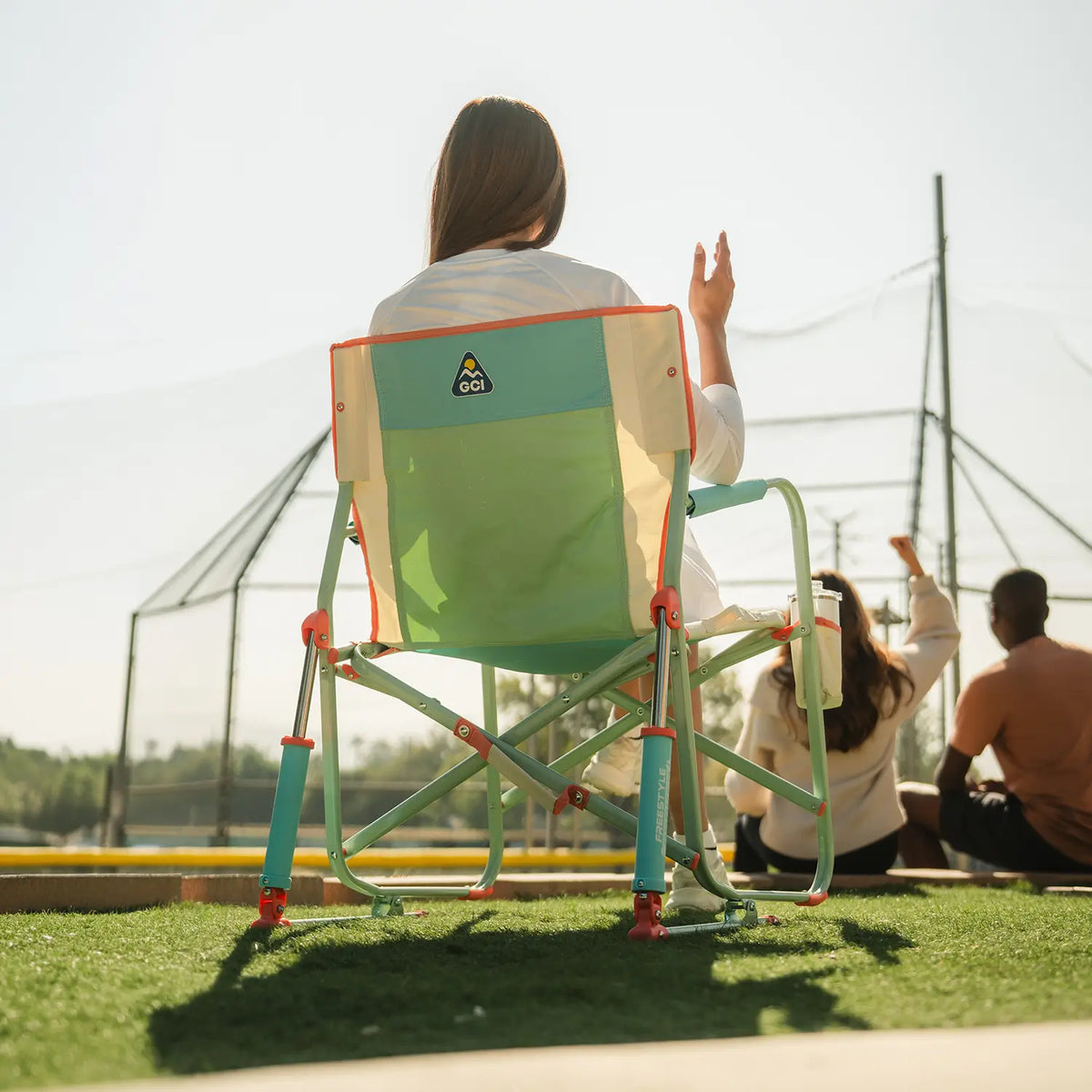A woman sitting and cheering on a baseball game in an ivory Freestyle Rocker. 