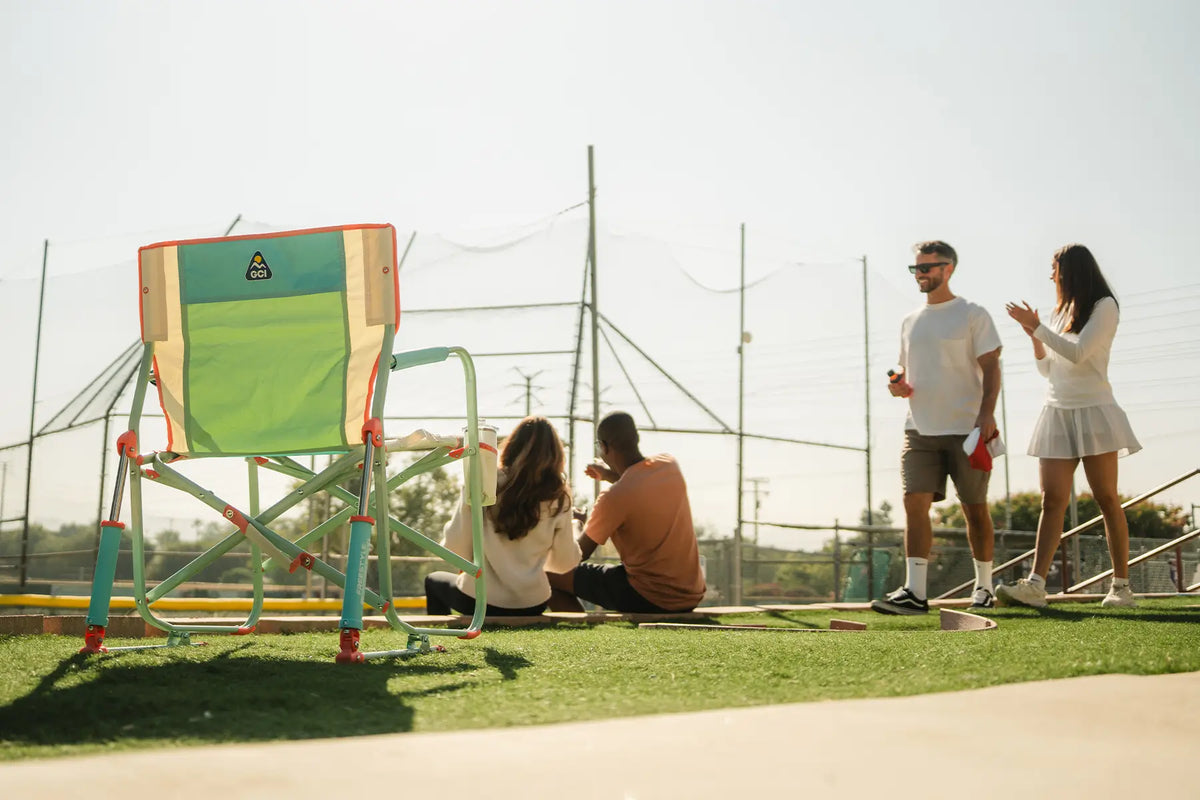 An ivory Freestyle Rocker chair positioned next to a group of baseball fans watching a game. 
