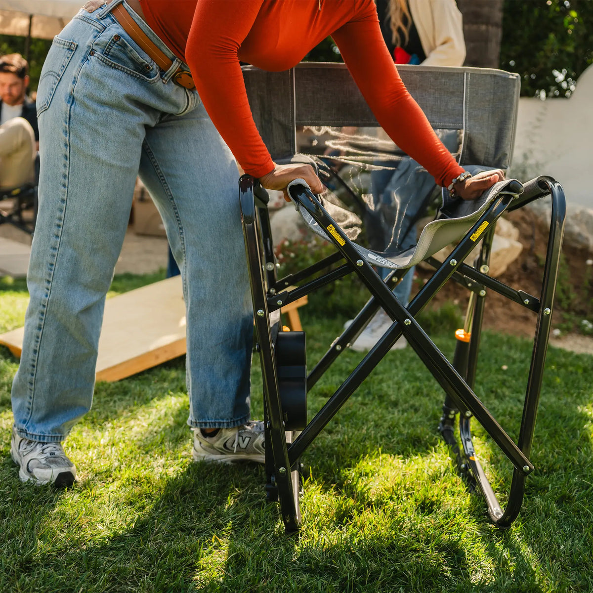 A woman closing up a gray freestyle rocker with side table using the eazy fold technology. 