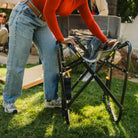 A woman closing a Freestyle Rocker with Side Table by pulling the seats eazy fold handles. 