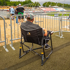 A man watching cars race on a track while sitting in a black Freestyle Rocker XL chair. 