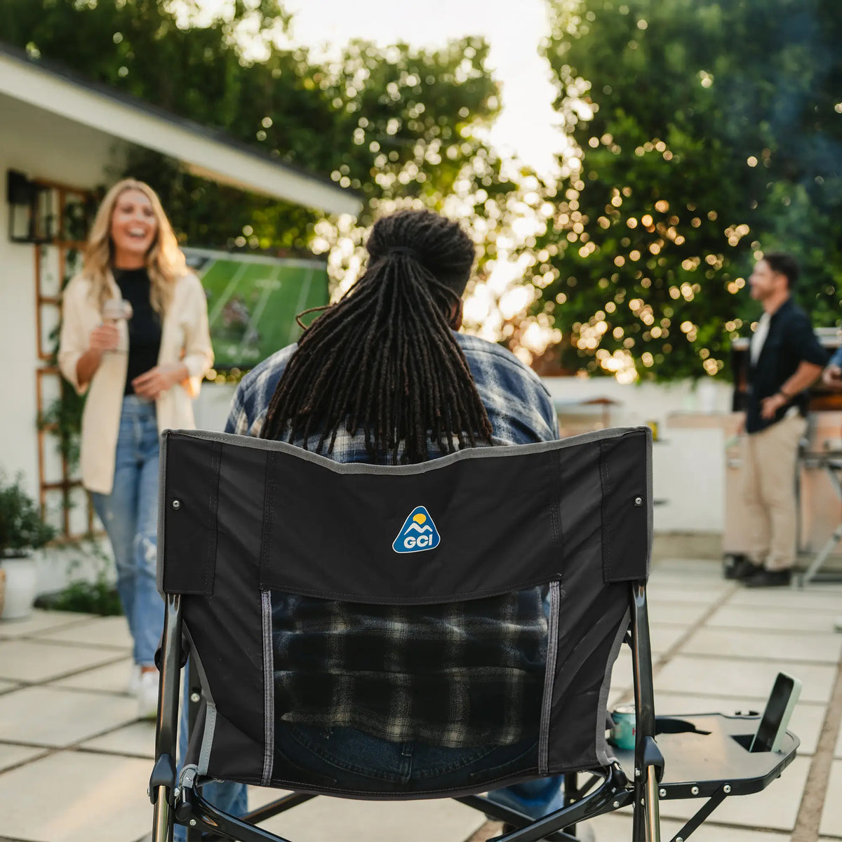 The back of a man watching a football game while sitting in a black freestyle rocker xl with side table. 