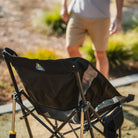 A GCI Outdoor Pod Rocker Elite from the back, showcasing its black mesh fabric and sturdy frame in an outdoor setting.