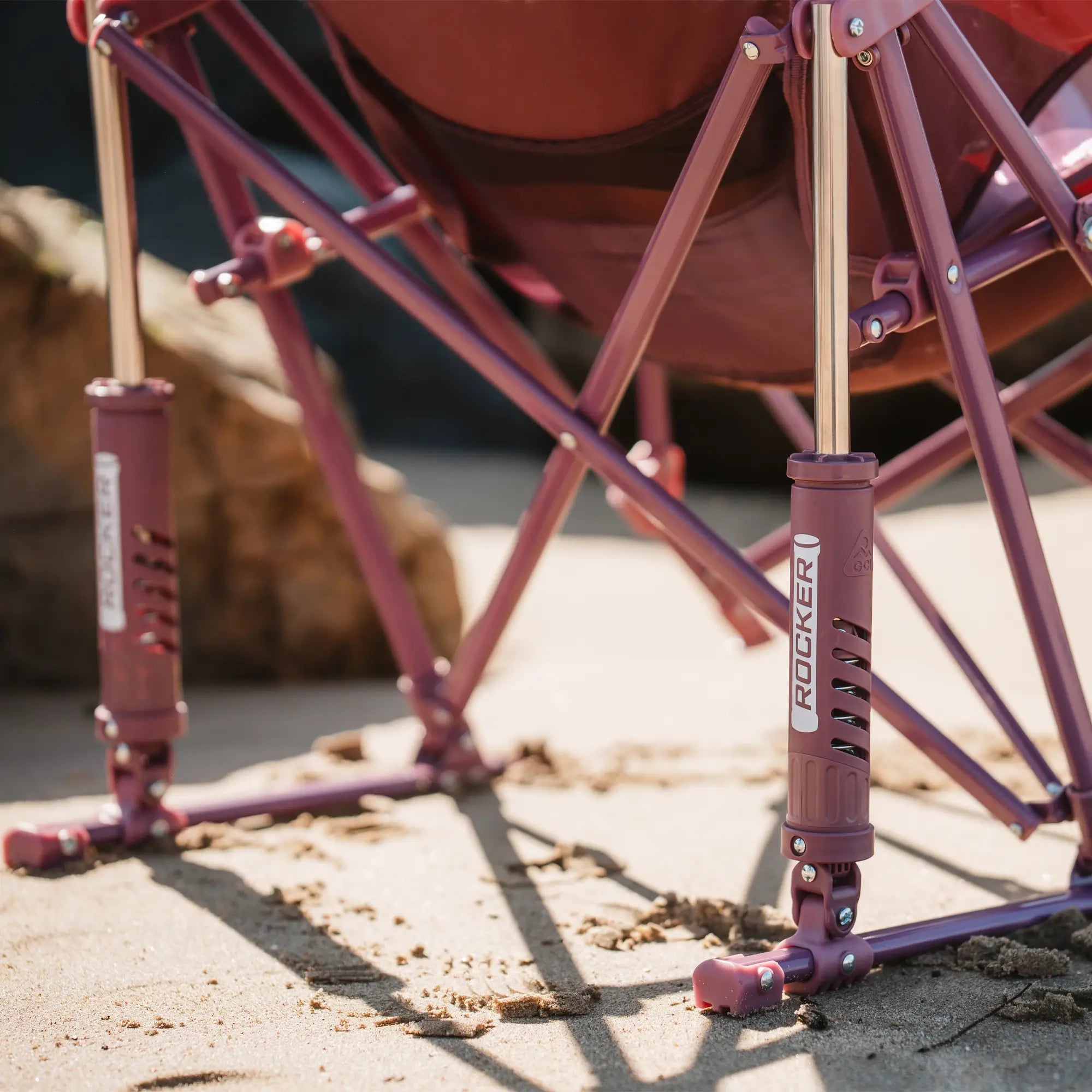 Close-up of the GCI Outdoor Pod Rocker Elite's spring-loaded rocking mechanism, showing its durable construction on the sand.