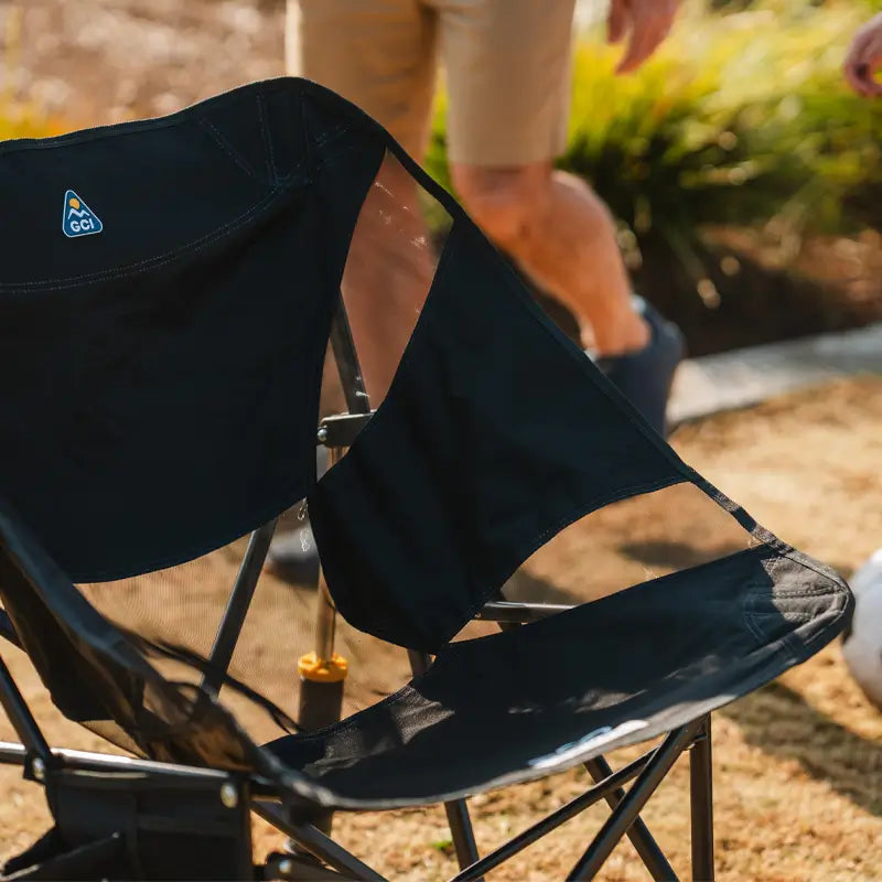 A close-up of the GCI Outdoor Pod Rocker Elite’s breathable mesh backrest, with a blurred figure walking in the background.