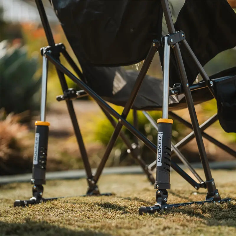 A detailed view of the GCI Outdoor Pod Rocker Elite’s spring-loaded rocking mechanism, showing its sturdy frame on grass.