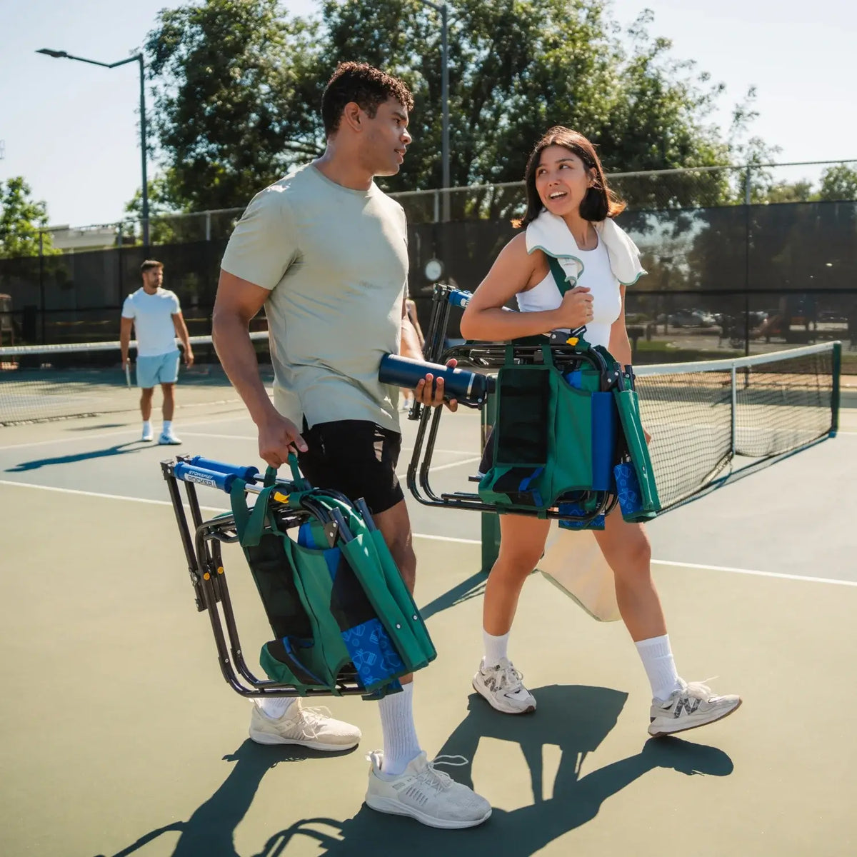 Two people carrying the pickleball stowaway rocker with shoulder straps and carry handle. 