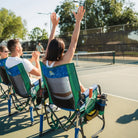 Three people sitting in a pickleball stowaway rocker while a woman cheers with her hands up. 