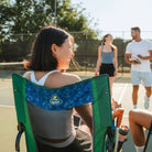 Woman laughing while sitting in pickleball stowaway rocker while people approach her. 