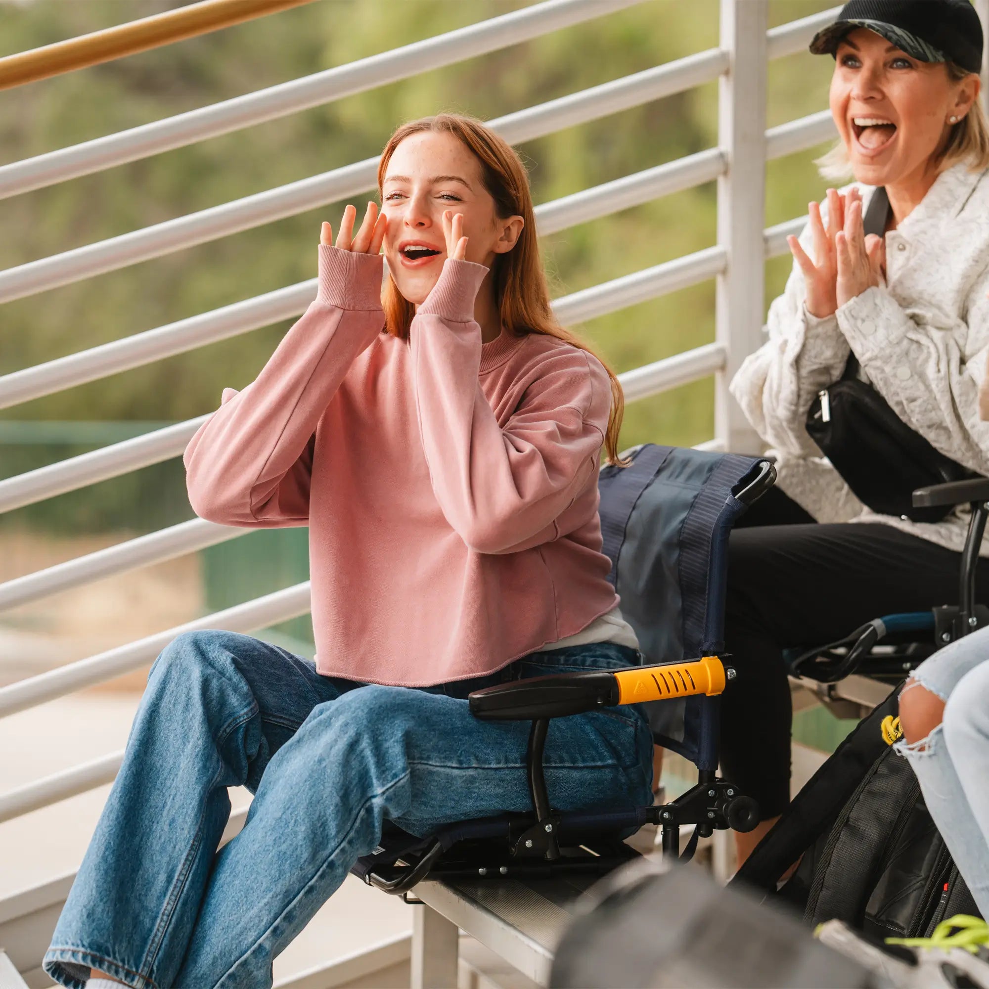 A young woman in a pink sweatshirt cheers in her GCI Outdoor Stadium Rock-Cliner, an adjustable, rocking bleacher seat.