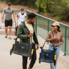 A couple carries GCI Outdoor Stadium Rock-Cliner chairs by shoulder straps, underscoring their portable, foldable construction.