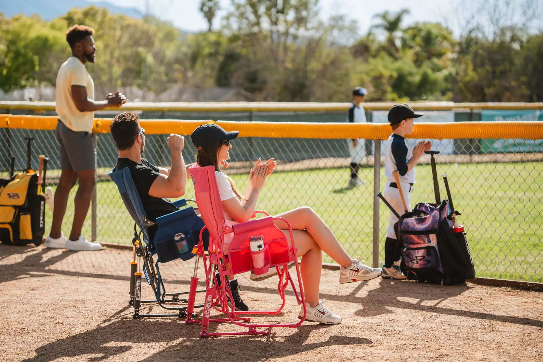 Couple cheering on baseball team while sitting by field. 